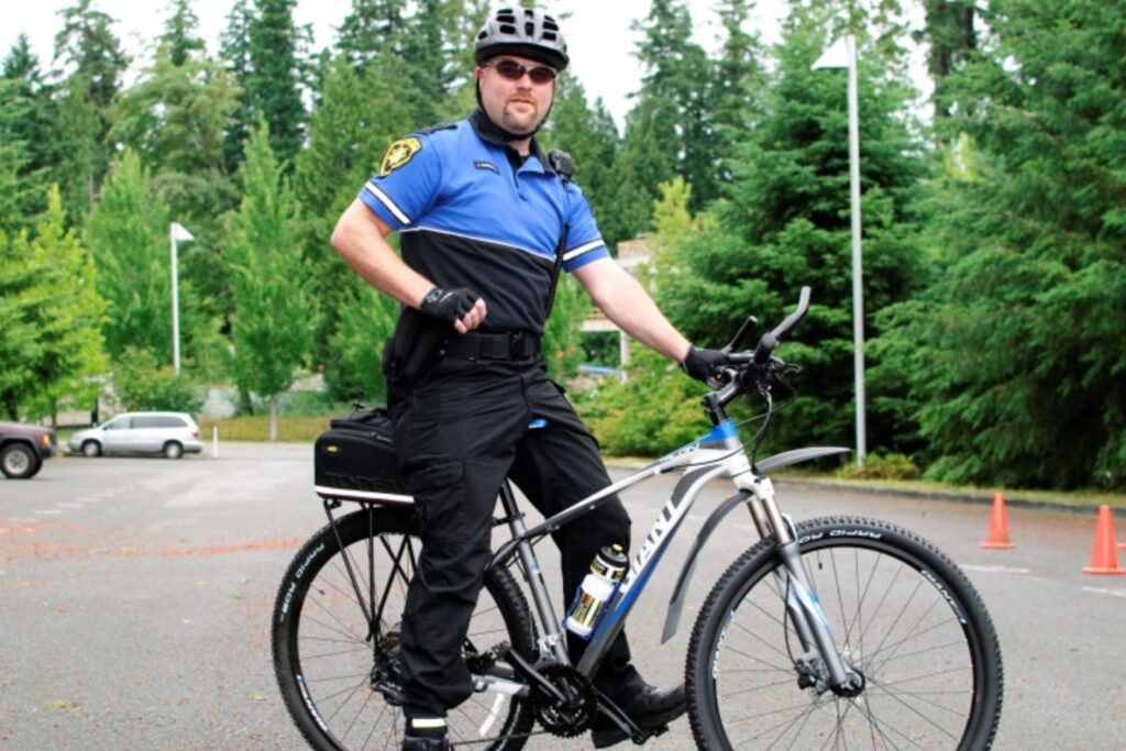 Police officer in uniform standing with a bicycle outdoors