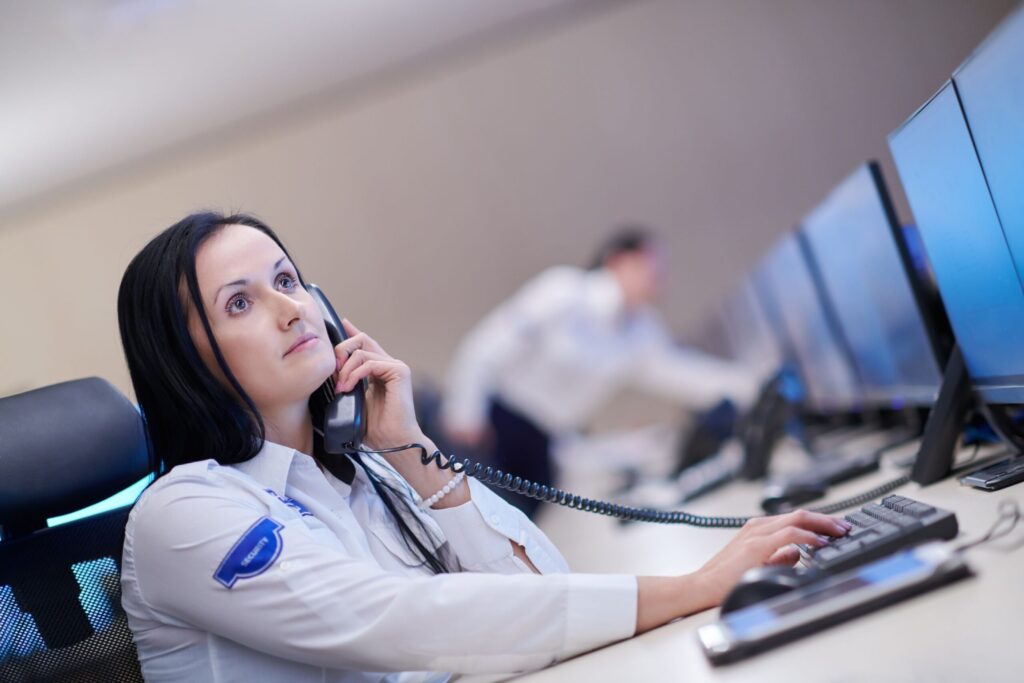 Female security operator answering calls in front of screens