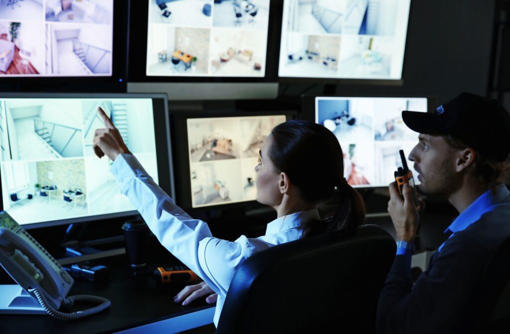 Security personnel monitoring multiple surveillance screens